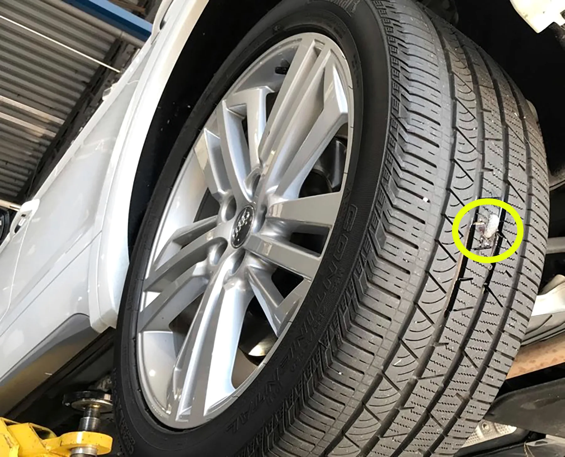 Schroef in het loopvlak van een autoband, gemarkeerd met een gele cirkel