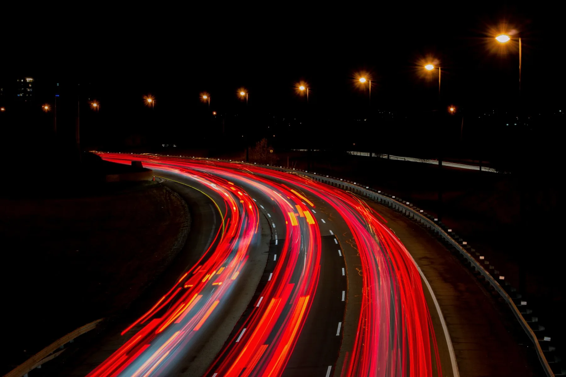 Lichtsporen van auto's op een bochtige weg bij nacht